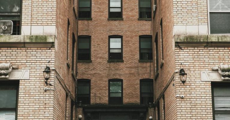 Door - Person Standing Between Brown Concrete Building